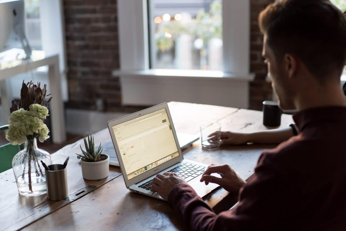 Person using laptop sat on a wooden bench