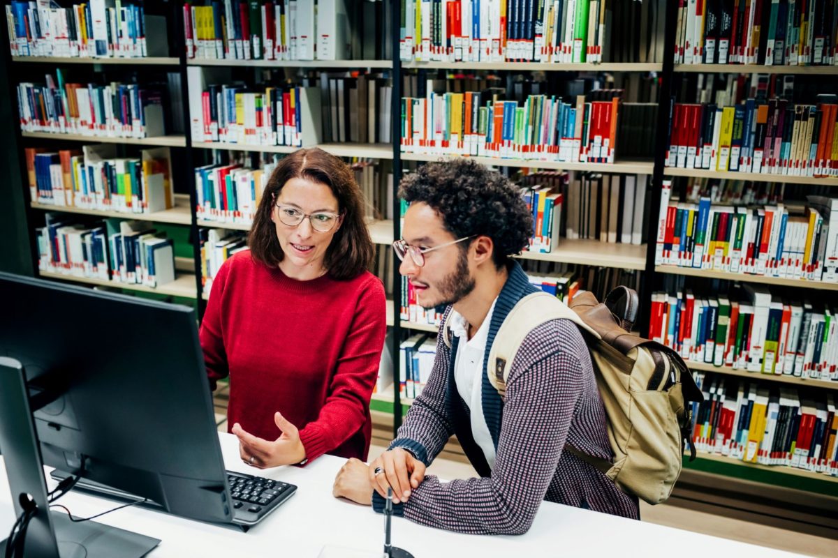 Librarian helping student locate online resources for his studies