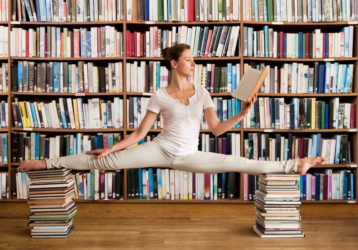 Managing risks of AI in libraries. Woman balancing on two stacks of books.