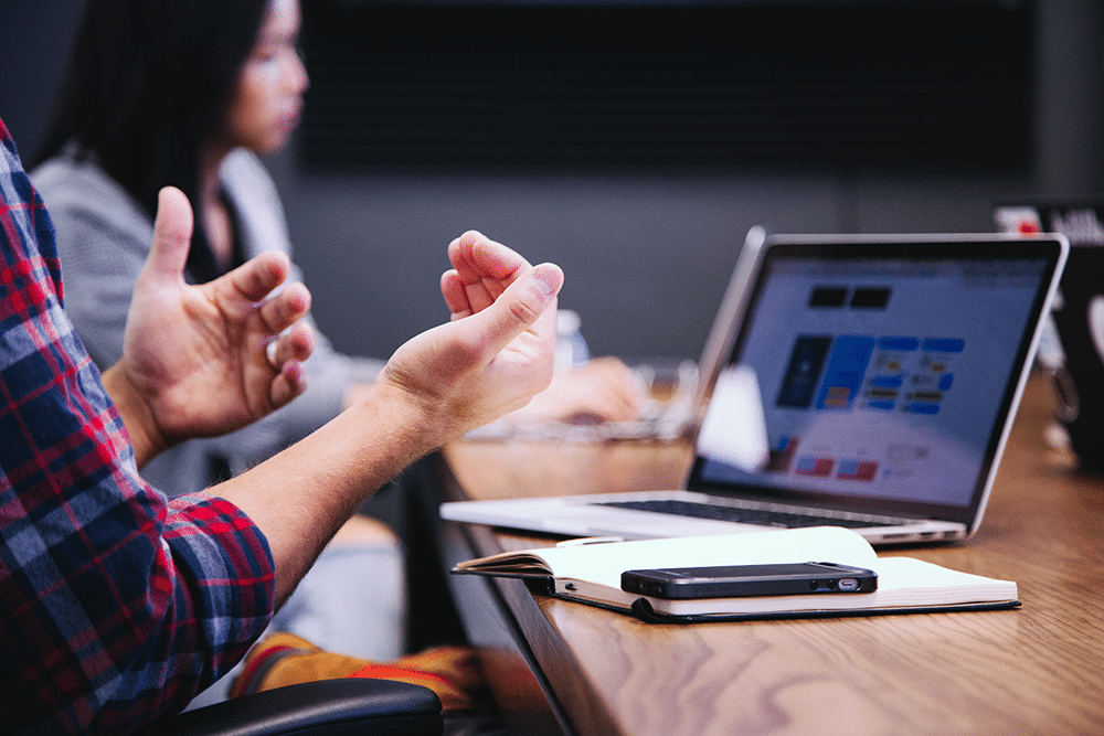 People sat at a laptop gesturing with hands